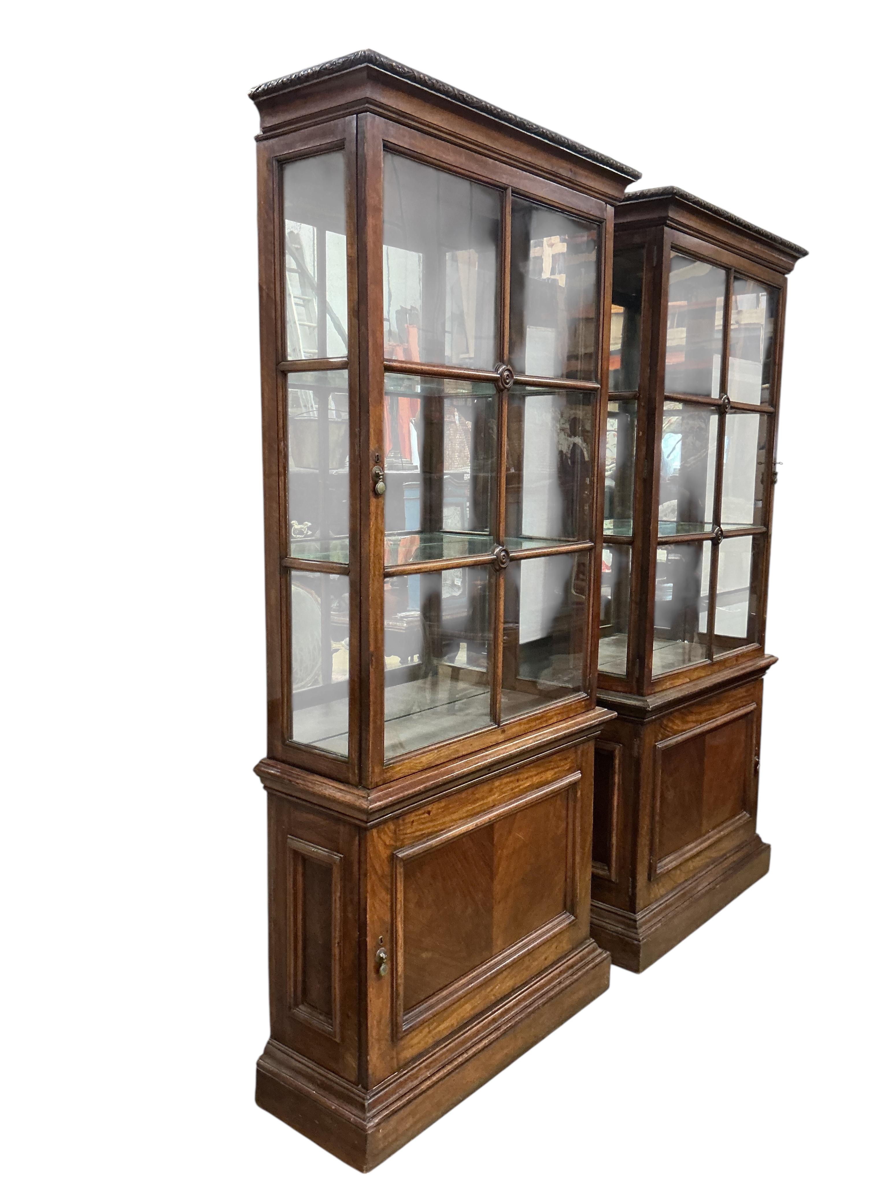 A pair of 1930's walnut vitrines, with single bar glazed doors over single panelled doors, on plinth feet, width 94cm, depth 35cm, height 212cm